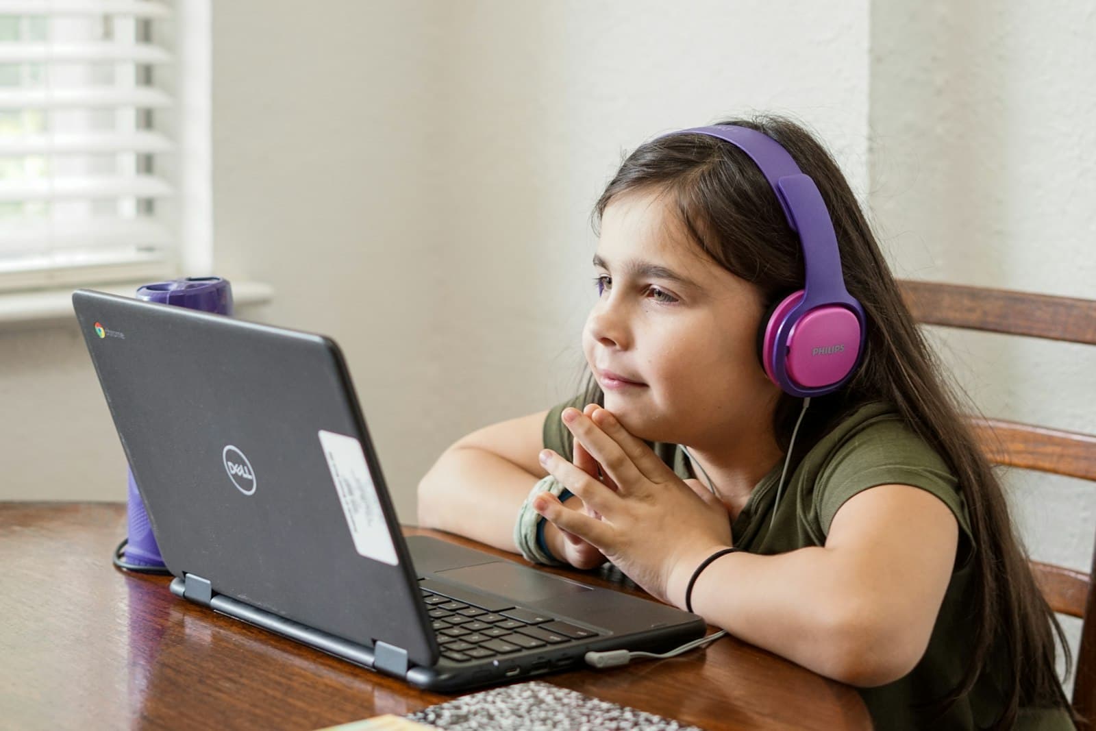 A young learner wearing headphones, focused on a laptop lesson